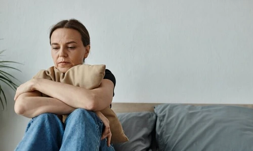 Nettoyage des lieux - photo d'une personne triste assise sur son lit, qui ne se sent pas bien chez elle